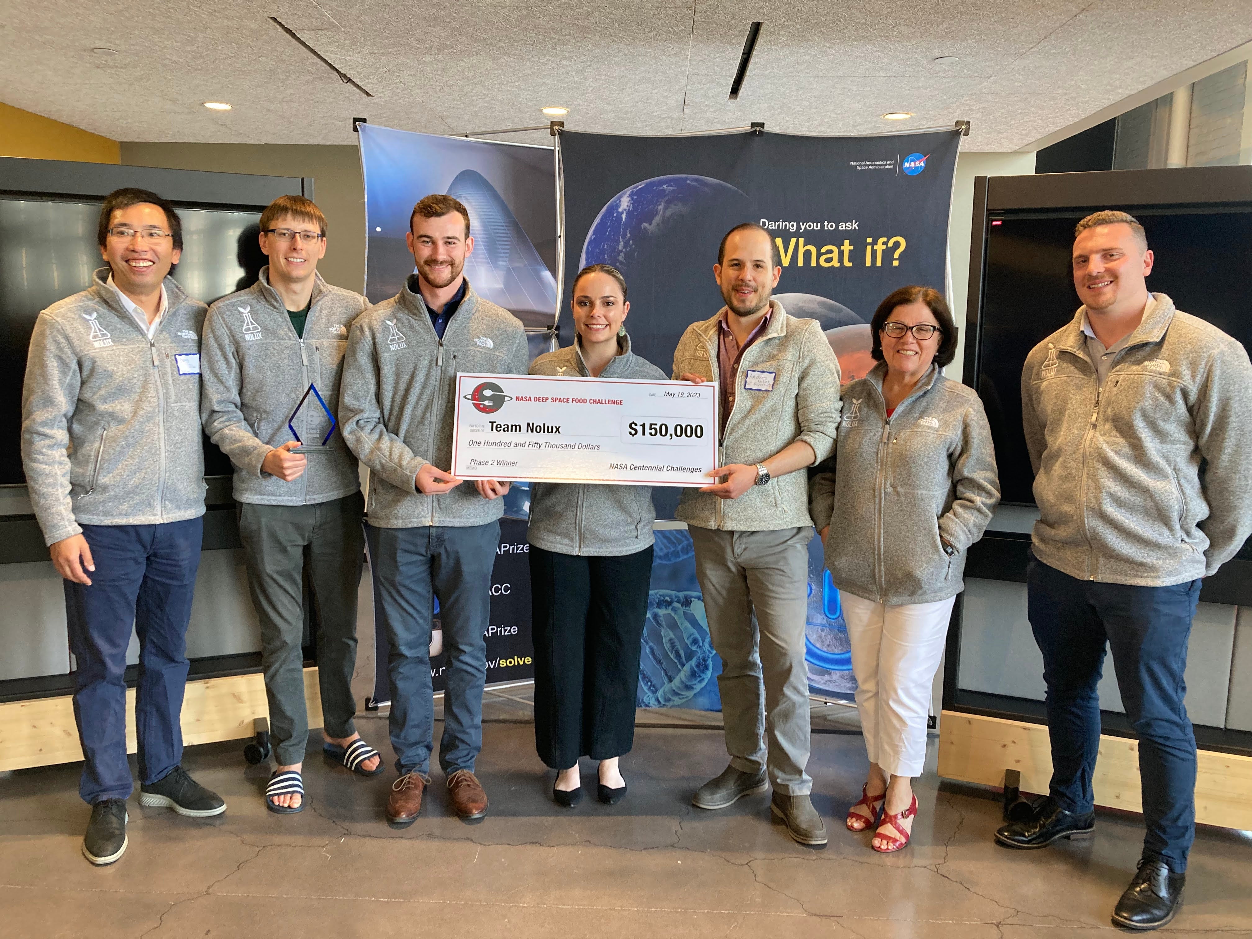 Team NoLux receiving a monetary award as one of the NASA Deep Space Food Challenge finalists via their solution involving artificial photosynthesis. Left to right: Jiao, F., Jinkerson, R.E., Harland-Dunaway M., Shelton A., Narvaez, A.F., Le, D.N., Orozco-Cárdenas, M.L., and Crandall B. NASA Deep Space Food Challenge public awards ceremony and exhibition. Brooklyn, NY, May 19, 2023.